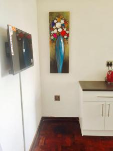 a kitchen with a painting of a blue vase on the wall at Modern rooms available close to the beach in Humewood in Port Elizabeth