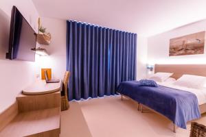 a bedroom with a bed and a desk and a television at ManavaHotel in Herstal