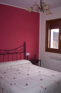 a bedroom with a white bed with a red wall at Apartamentos Arcos de Solana in Vilas del Turbon