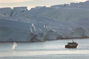 a boat in the water next to a iceberg at Hotel Icefiord in Ilulissat