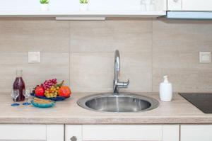 a kitchen sink with a bowl of fruit and wine glasses at Skopelitis Village in Katapola
