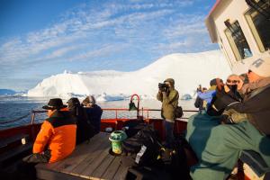 a group of people on a boat in front of an iceberg at Hotel Icefiord in Ilulissat