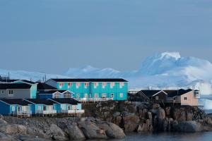 a group of houses on rocks with a mountain in the background at Hotel Icefiord in Ilulissat