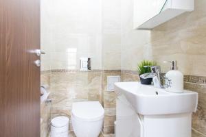 La salle de bains est pourvue de toilettes blanches et d'un lavabo. dans l'établissement Domus Apartments Old Town, à Plovdiv