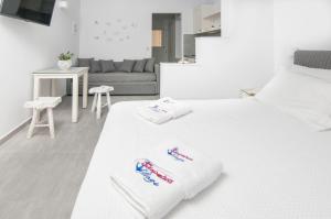 a white bedroom with two beds and a couch at Skopelitis Village in Katapola