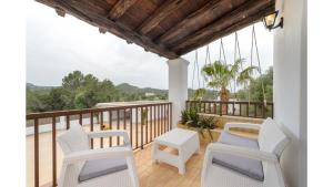 a balcony with white chairs and a wooden ceiling at Can Mestre is a huge Villa with stunning sunset views near to San Antonio in San Antonio Bay