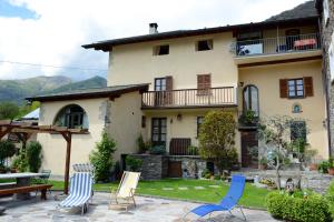 ein Haus mit Stühlen und einem Tisch im Hof in der Unterkunft Casa Dolce Casa in Vercana