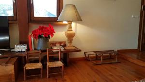 a room with a table with a lamp and a vase with red flowers at Casa con encanto, jardín, vistas y piscina in Estavar +19 photos