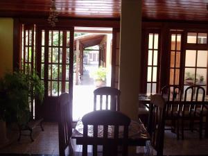 a dining room with a table and chairs and a glass door at Pousada da Lenna in Rio das Ostras