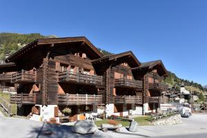 グリメンツにあるApartments Vieux Chaletの山の上にバルコニー付きの大きな木造の建物