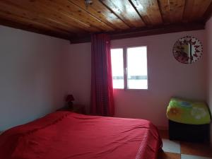 a bedroom with a red bed and a window at Le Moutardier in Cilaos