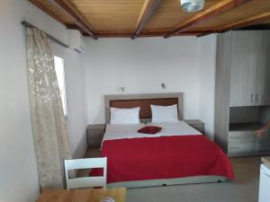 a bedroom with a large bed with a red blanket at Hotel Aglaia in Kalamaki