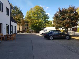 ein schwarzer Wagen neben einem Gebäude mit einem Van geparkt in der Unterkunft Pension am Filmpark in Potsdam