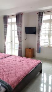 1 dormitorio con cama rosa y TV de pantalla plana en Nhà Nghỉ Hoàng Hoa, en Buon Ma Thuot