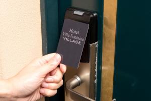 a person holding a card in front of a door at Hotel Villa Fontaine Tokyo-Hamamatsucho in Tokyo