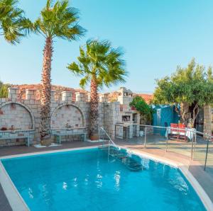 a swimming pool with palm trees and a building at Luxury Villa Karteros in Karteros