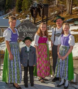 una familia posando para una foto delante de un cartel en Gästehaus Lipp, en Mittenwald