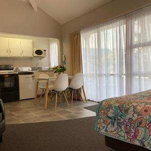 a hotel room with a bed and a table and chairs at Cameron Thermal Motel in Tauranga