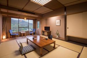 ein Wohnzimmer mit einem Tisch, Stühlen und einem TV in der Unterkunft Hotel Senshukaku in Hanamaki