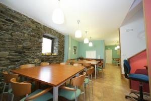 a room with tables and chairs and a stone wall at Albergue O Durmiñento in Sarria