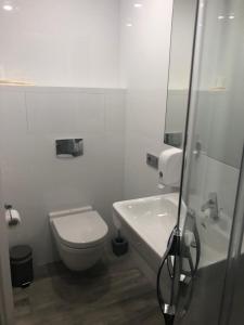 a white bathroom with a toilet and a sink at StanGret Hotel in Kyiv