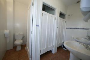 a white bathroom with a toilet and a sink at Albergue O Durmiñento in Sarria