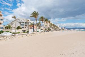 una playa de arena con palmeras y edificios en Apartment Muchavista 3 bed 2 bath, en El Campello