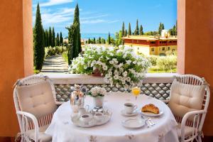 a table with a white table cloth and cups and saucers on a balcony at Villa Telli in Garda