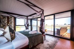 1 dormitorio con cama con dosel y balcón en The Namushasha River Villa, en Kongola