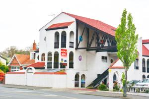 ein weißes Gebäude mit rotem Dach auf einer Straße in der Unterkunft Alcala Motor Lodge in Dunedin