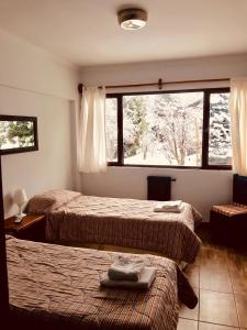 a hotel room with two beds and a window at Hosteria de la Villa - Moonski in San Carlos de Bariloche