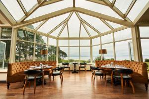 a dining room with tables and chairs and windows at Golf View Hotel & Spa in Nairn