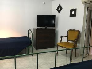 Zimmer mit einem Bett, einem TV und einem Stuhl in der Unterkunft Porto in Vista in Monopoli