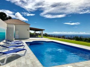 a pool with chairs and the ocean in the background at Villa Javier La Palma in El Paso