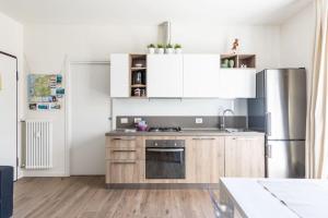 a kitchen with white cabinets and a stainless steel refrigerator at Appartamenti 1 in Dervio