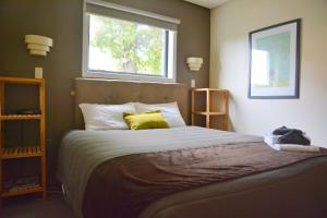 a bedroom with a large bed with two windows at George Street Motel Apartments in Dunedin