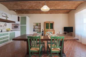 a kitchen with a large wooden table with green chairs at Terre di GIORGIO Agriturismo Villa la Palazzetta in Castiglione dʼOrcia