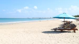 a row of chairs and an umbrella on a beach at CassaMia Bali - Spacious Luxury 5 Bedroom Villa in Jimbaran