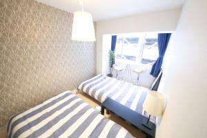 a bedroom with two beds and a window at Guest House Re-worth Yabacho1 301 in Nagoya