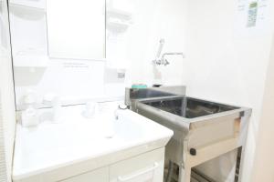 a white bathroom with a sink and a mirror at Guest House Re-worth Yabacho1 301 in Nagoya