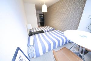 Dos camas en una habitación pequeña con una mesa. en Guest House Re-worth Yabacho1 301, en Nagoya