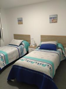 two beds sitting next to each other in a room at Apartamento Camelle in Camelle