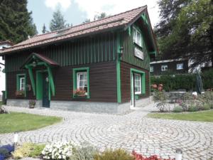 ein kleines grünes Haus mit einem gepflasterten Hof in der Unterkunft Ferienhaus "Jägers Ruh" in Wernigerode
