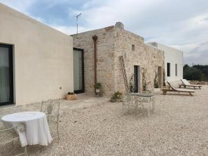 patio z krzesłami i stołem oraz budynek w obiekcie Relais Grottone w mieście Ostuni