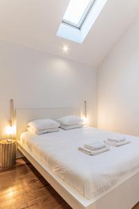 a bedroom with a white bed with a skylight at LX 77 in Lisbon