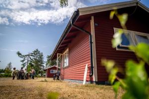 un grupo de personas de pie fuera de una casa roja en Haga Park Camping & Stugor, en Mörbylånga