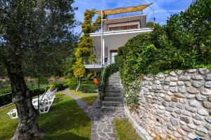 ein Haus mit einer Treppe und einer Steinmauer in der Unterkunft La Villa Fasano in Gardone Riviera