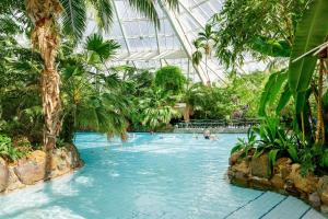 a pool in a greenhouse with people swimming in it at Hotel Bispinger Heide by Center Parcs in Bispingen