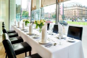 a long table in a restaurant with chairs and flowers at Millennium Hotel Glasgow in Glasgow