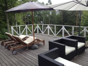 a deck with two lounge chairs and an umbrella at Country House by the lake in Hästveda